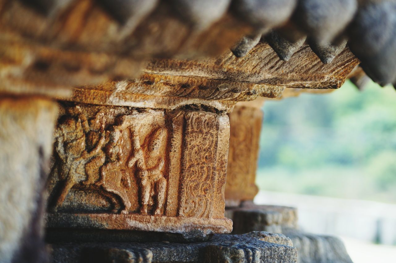 focus on foreground, close-up, selective focus, wood - material, old, day, animal themes, art and craft, weathered, outdoors, wall - building feature, art, built structure, no people, animals in the wild, stone material, rusty, architecture, one animal, religion