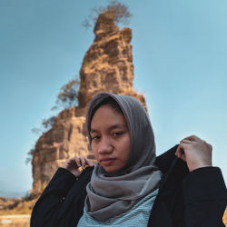 Portrait of young woman standing against sky