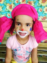 Close-up portrait of cute girl with painted face sitting on bench