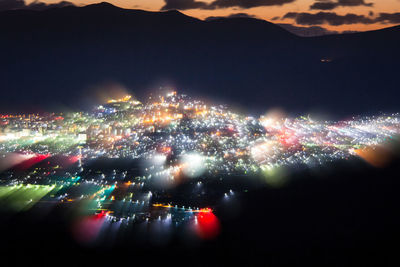 Aerial view of illuminated cityscape against sky at night