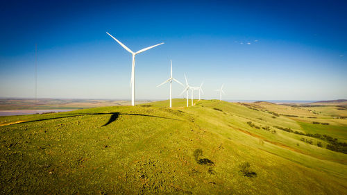 Wind turbines on field against sky