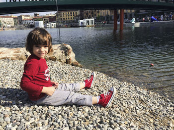 Boy sitting on pebbles at beach