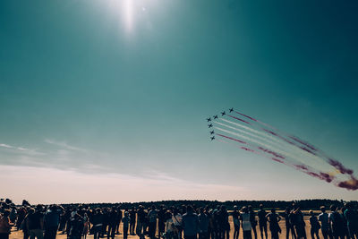 Crowd watching airshow against blue sky