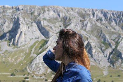 Woman holding umbrella while standing on mountain