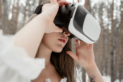 Woman wearing virtual reality simulator against trees outdoors