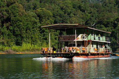 People in boat on river against trees