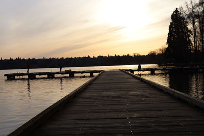 Pier over lake against sky during sunset