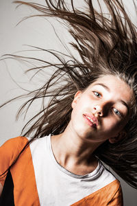 Portrait of girl tossing hair against white background