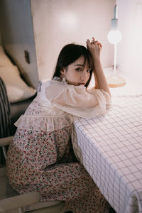 Young woman sitting on bed at home