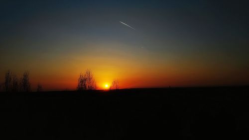 Scenic view of silhouette field against sky at sunset