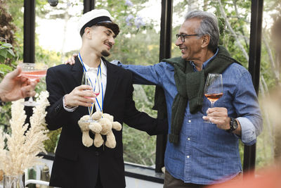 Smiling men with arms around each other at summer party