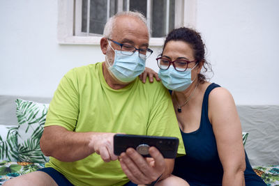 An elderly couple with surgical masks while using a mobile phone. elderly people