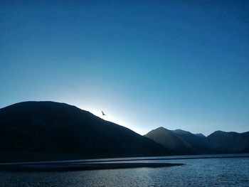 Scenic view of lake and mountains against clear blue sky