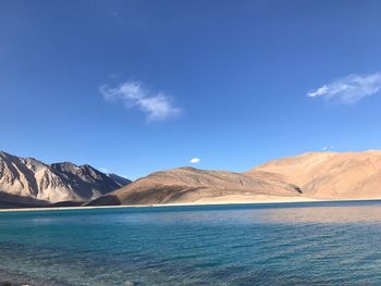 Scenic view of lake and mountains against blue sky