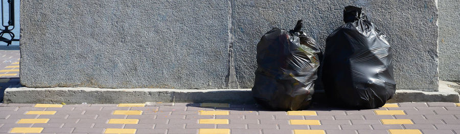 Low section of people standing on sidewalk against wall