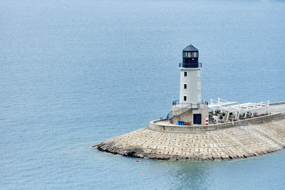 Lighthouse by sea against building