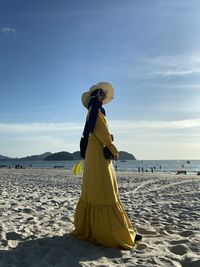 A muslim lady walk around the beach while wearing a yellow dress