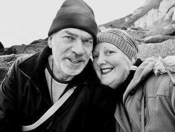 Close-up portrait of cheerful mature couple wearing warm clothing at beach
