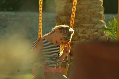 Girl sitting on swing in playground