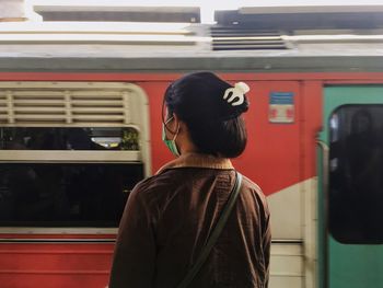 Rear view of man standing by train at railroad station