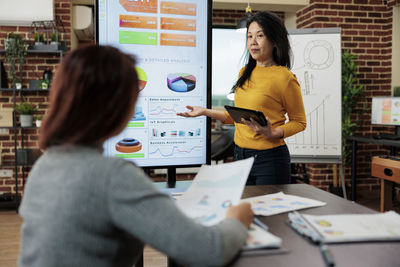 Woman explaining chart and graphs to colleagues at office