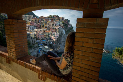 Woman sitting by built structure