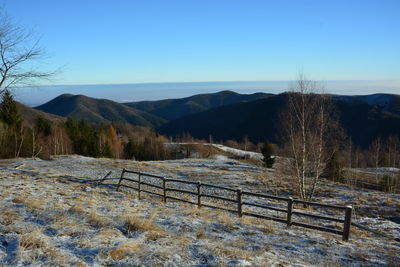 Scenic view of field by mountains against clear blue sky