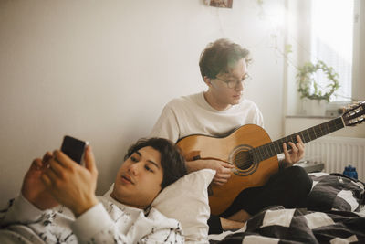 Rear view of boy holding guitar at music concert