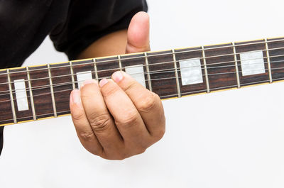 Close-up of man playing guitar against white background