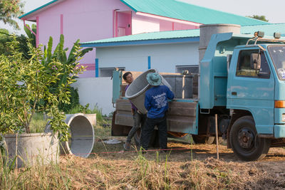 Man and cart by plants against building