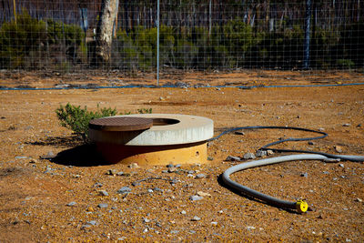 Abandoned chair by fence on field