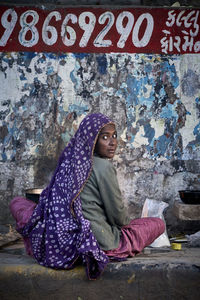 Portrait of woman sitting on wall