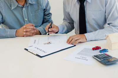Midsection of man reading book on table