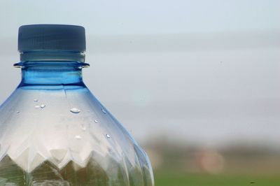 Close-up of wet plastic bottle against blue sky