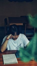 Side view of woman reading book at home