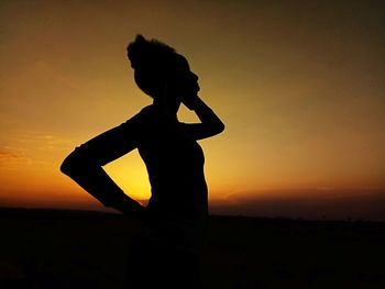 Silhouette woman standing against sky during sunset