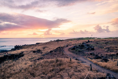 Road by sea against sky during sunset