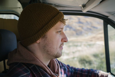Side view of young man looking away while sitting in car
