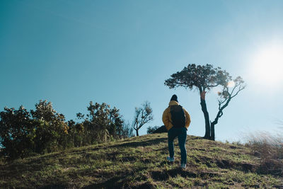 Rear view of man walking on field against sky