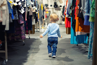 Rear view of boy amidst clothes in store