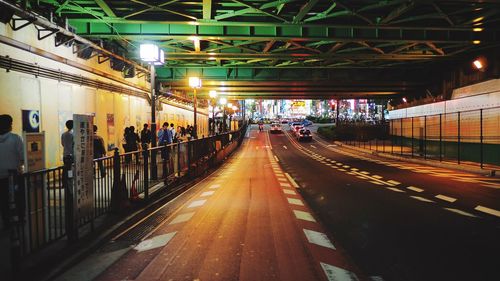People on illuminated road in city at night