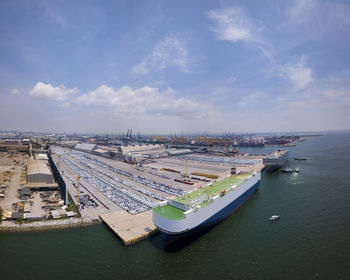 Aerial logistics commercial vehicles waiting to be load on to a car carrier ship at dockyard