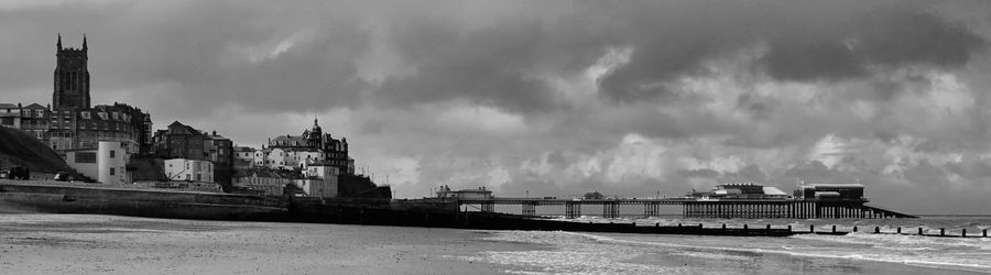 Panoramic view of buildings against cloudy sky