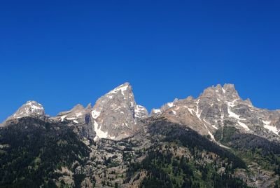 Low angle view of mountain range against clear blue sky