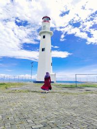 Lighthouse by sea against sky