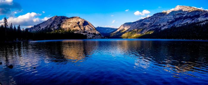 Scenic view of lake and mountains against blue sky