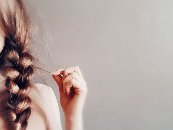 Midsection of woman holding hair against wall