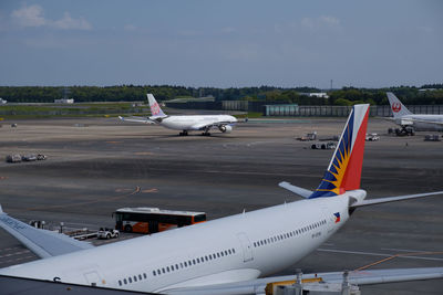 Airplane flying over airport runway against sky