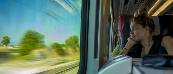 Young woman looking through window while traveling in train