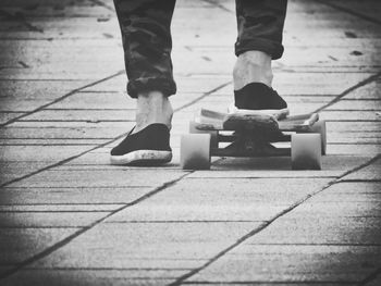 Low section of man with skateboard on footpath